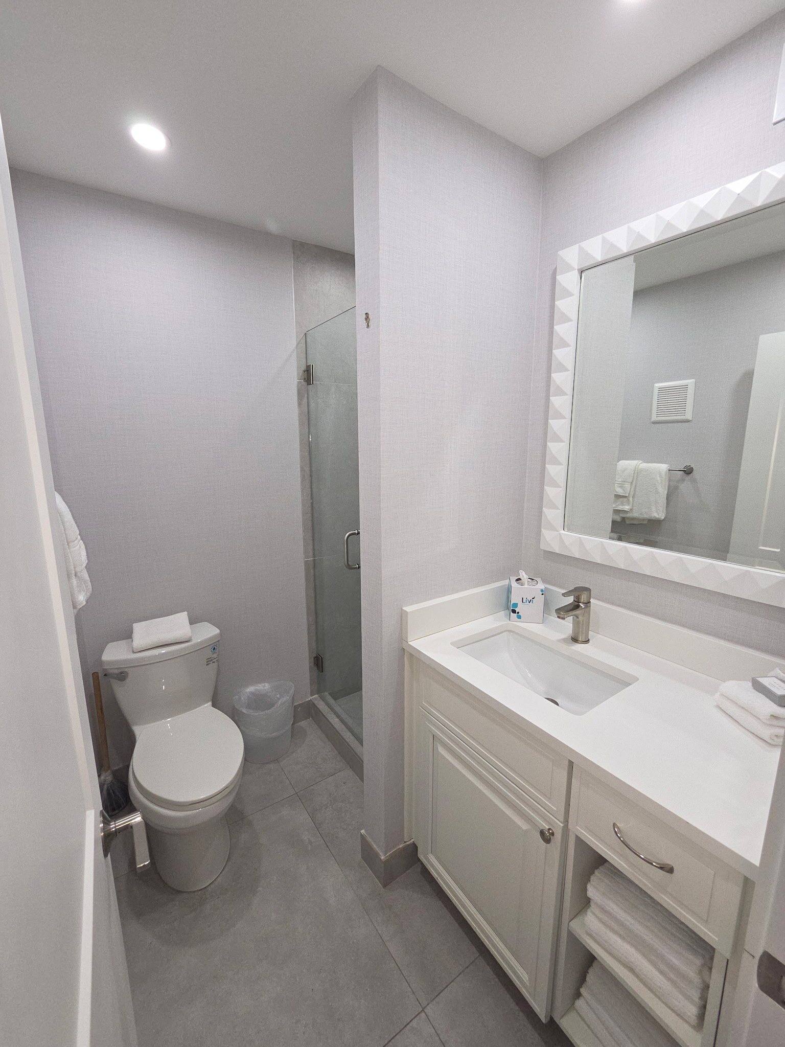 Deluxe Townhouse downstairs full bathroom off the foyer, with a white vanity and glass shower
