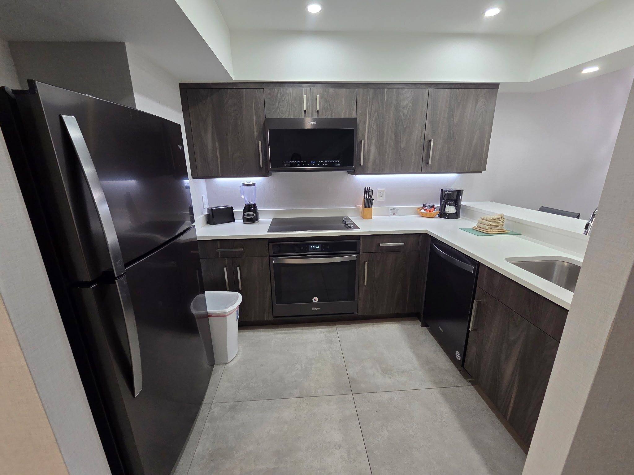 Renovated Deluxe Townhouse kitchen with dark wood cabinets, white counters and black stainless appliances