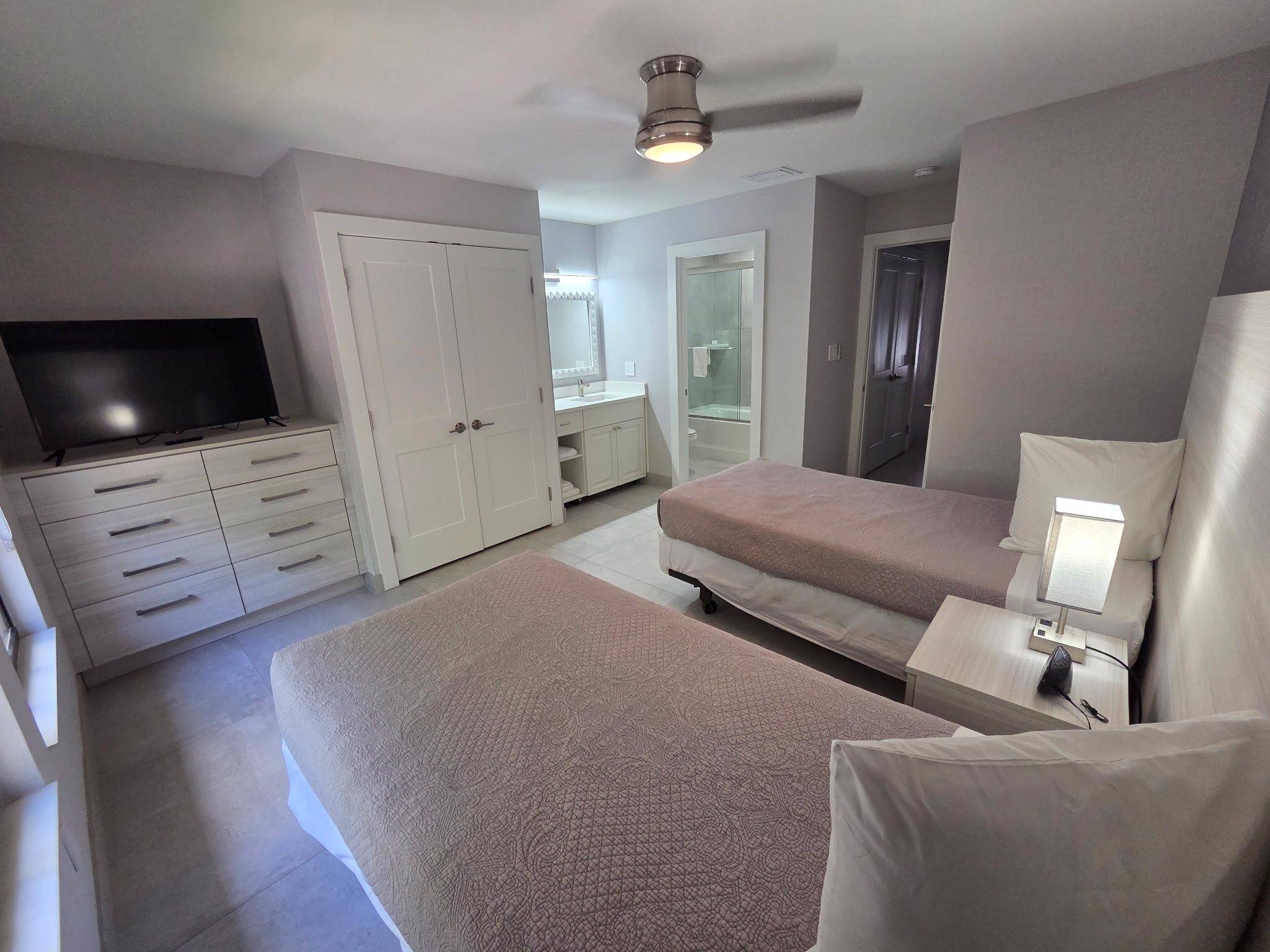 Deluxe Townhouse second bedroom with two twin beds, a dresser and a TV
