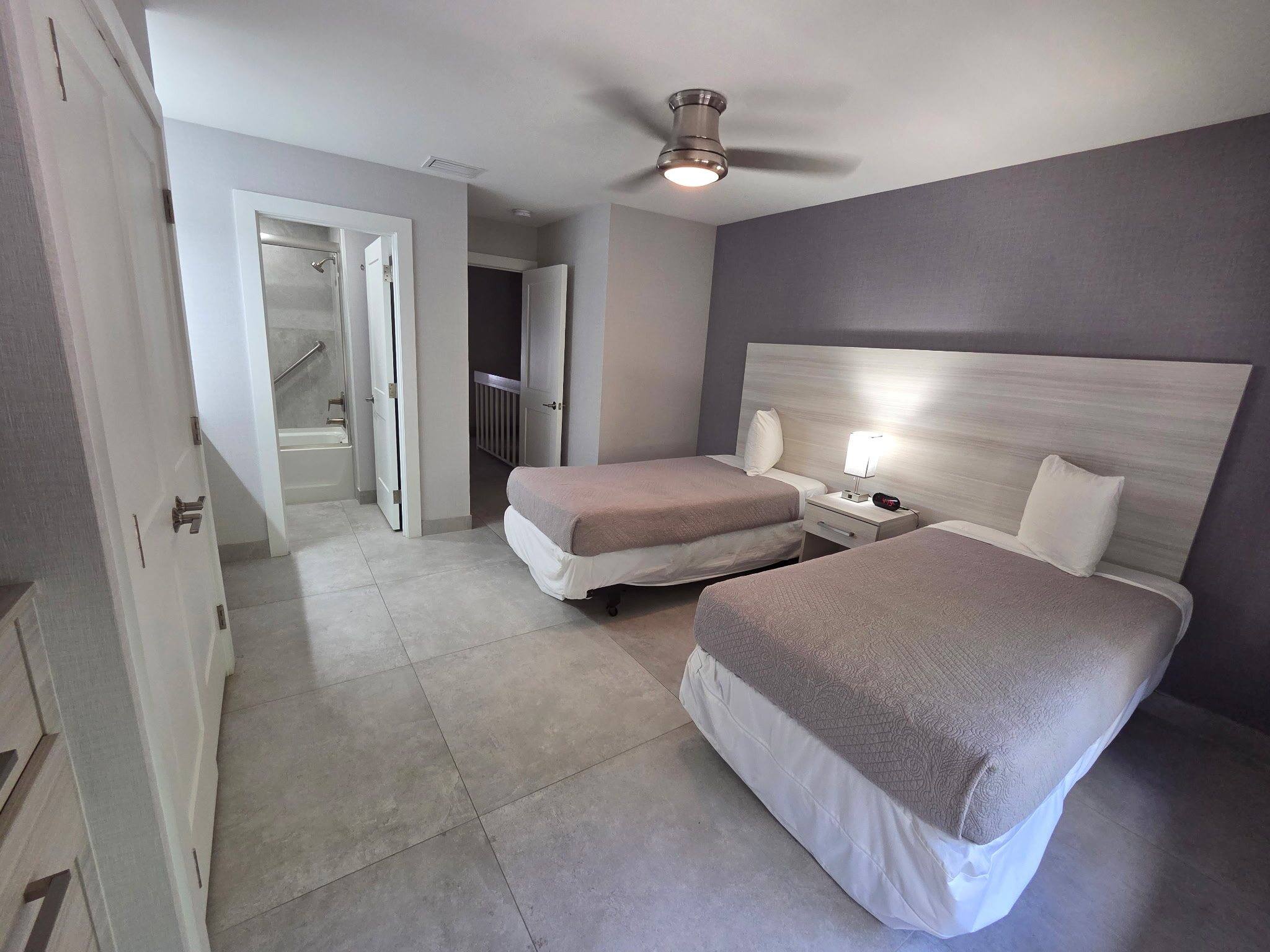 Deluxe Townhouse second bedroom with two twin beds and a ceiling fan