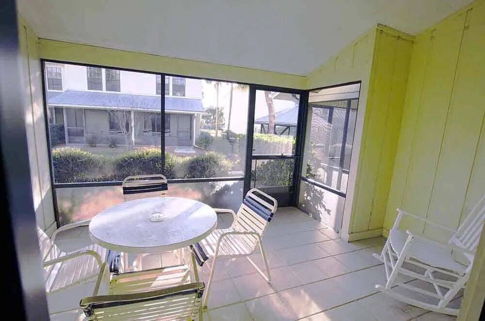 Townhouse screened porch with a round table, chairs and a rocking chair