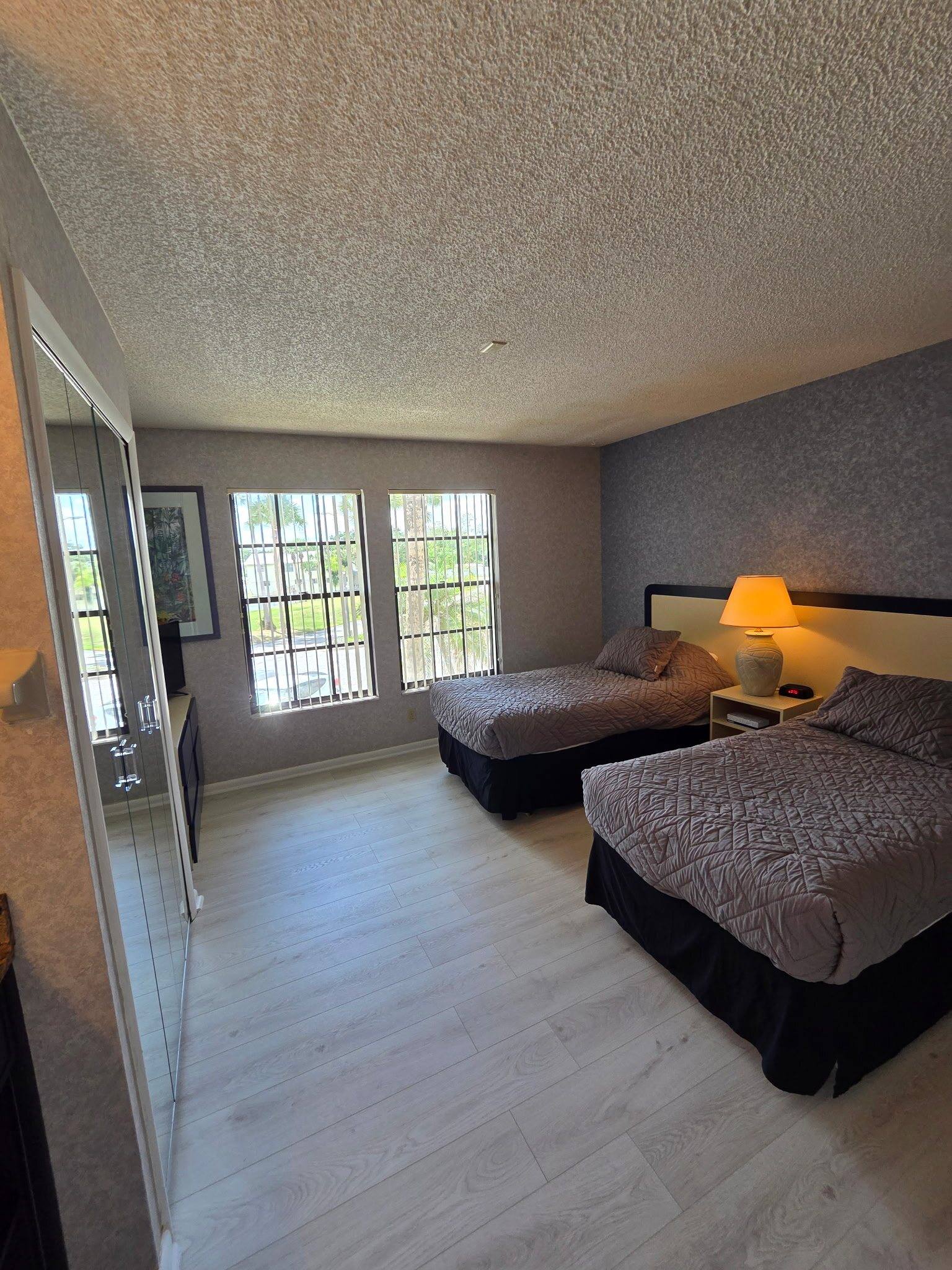 Townhouse second bedroom with two twin beds, mirrored closet doors and two windows