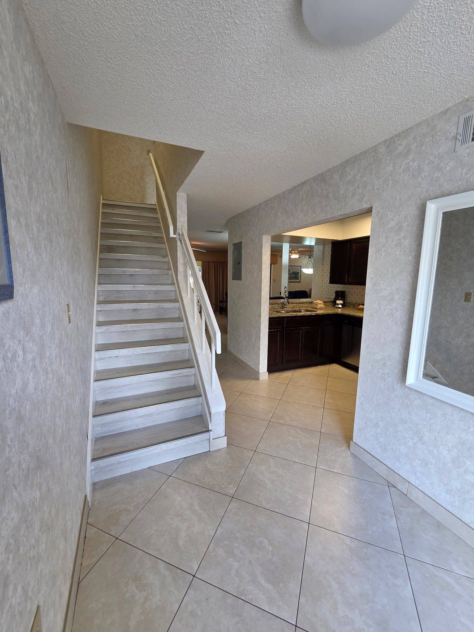 Townhouse entry with tile floors and the staircase to the bedrooms, kitchen beyond