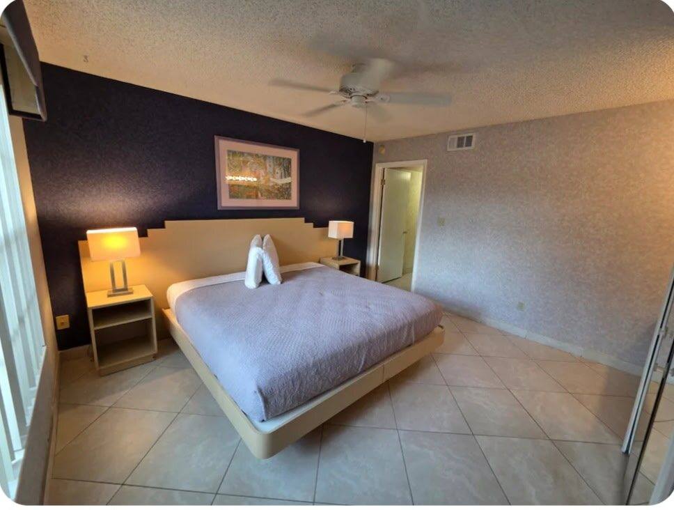 Villa bedroom with a bed, two bedside lamps and a dark accent wall