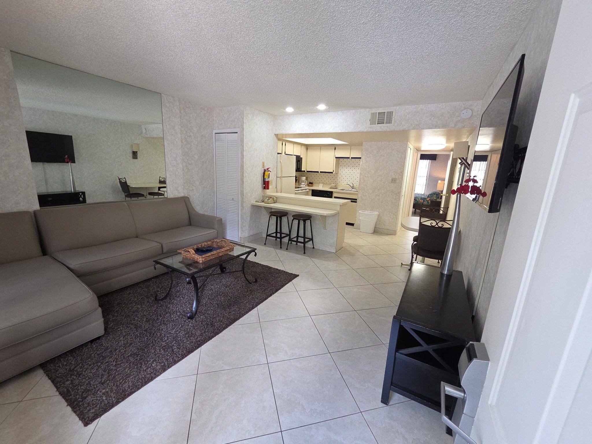 Villa living room with a sectional sofa and wall TV, open to the kitchen